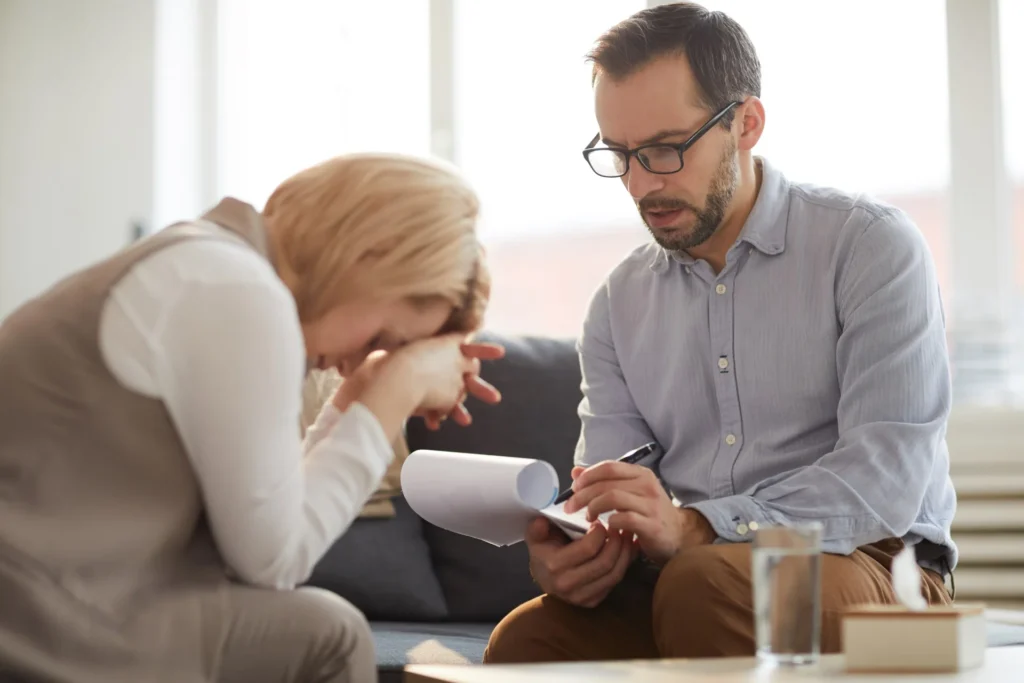 Terapeuta con bolígrafo y cuaderno tomando notas de un paciente con migraña
